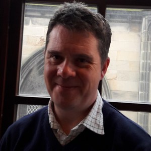 A photo of author Daibhidh Eyre standing in front of a window, with natural light illuminating his face. 