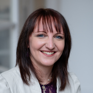 A portrait of author Shelagh Chaimbeul, showcasing her smiling confidently against a soft background. 